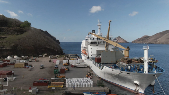 Nuku Hiva, cruise cargo ship discharging containers, Marquesas islands, aerial view by drone 2K7