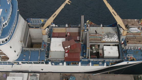 Nuku Hiva, cruise cargo ship discharging containers with crane, Marquesas islands, aerial view by drone 2K7