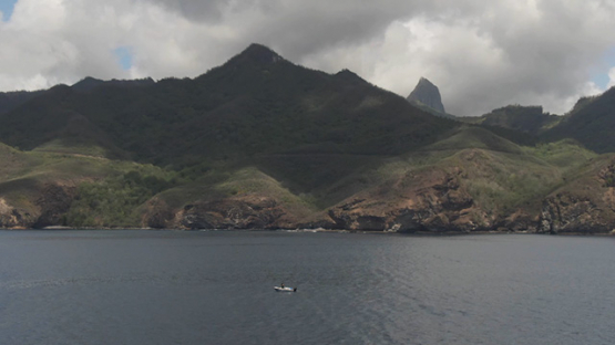 Aerial drone view of Ua Pou and mountains, motor boat by the coast line, Marquesas islands, Polynesia, 2K7