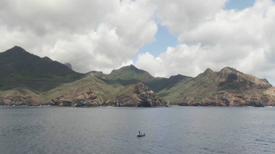 Aerial drone view of Ua Pou and mountains, motor boat by the coast line, Marquesas islands, Polynesia, 2K7