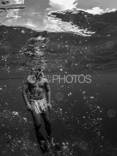 Polynesian guide of Bora Bora swimming underwater in the ocean, shot black and white