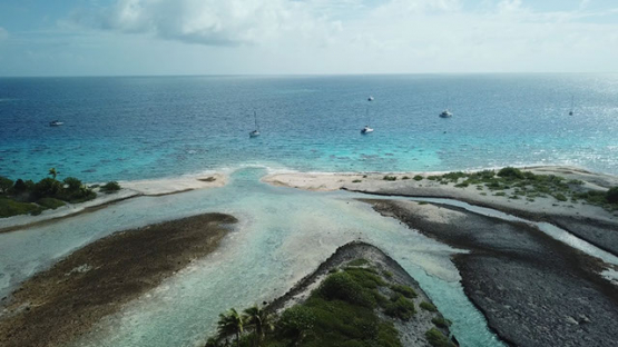 Aerial view by drone of atoll and sail boats anchored in the lagoon, 4K UHD