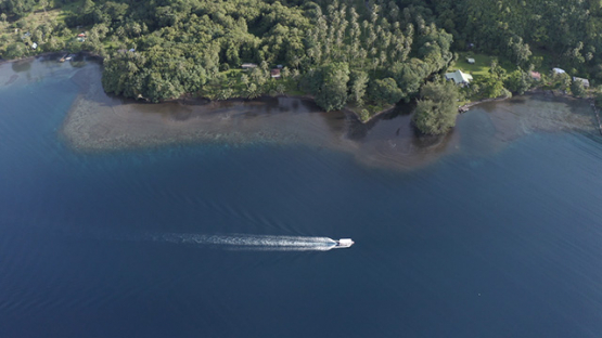 Tahiti, aerial view of Te Pari, motor boat sailing in the lagoon, 4K UHD