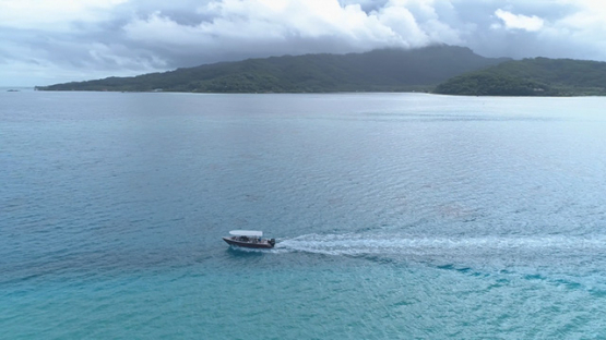 Tahaa island, aerial view of a motor boat navigating in the lagoon, 4K UHD