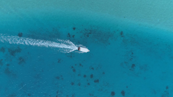 Tahaa, aerial view above a motor boat navigating in the lagoon, 4K UHD