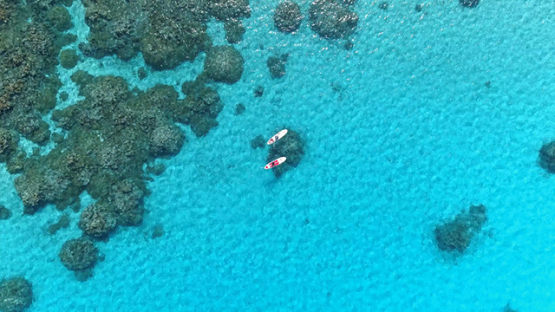 Bora Bora, aerial view above a couple of paddle boarders on the lagoon, 4K UHD