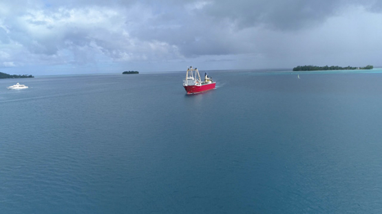 Bora Bora, aerial view of a cargo ship navigating in the lagoon, 4K UHD