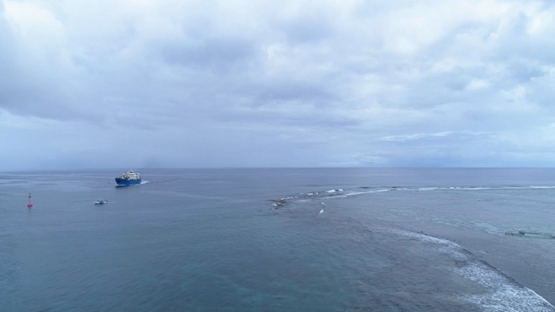 Bora Bora, aerial view of a cargo ship navigating in the pass, 4K UHD