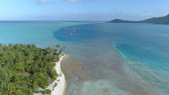 Maupiti, aerial view of the island and anchored sail boat in the lagoon, 4K UHD