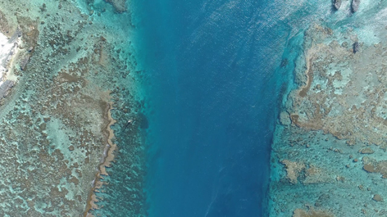 Maupiti, aerial view above the pass Onoiau and coral reef, 4K UHD
