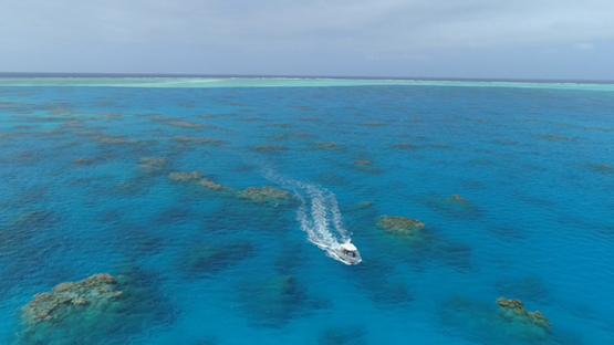 Tubuai, aerial view of a motor boat navigating among the coral pinnacles of the lagoon, 4K UHD