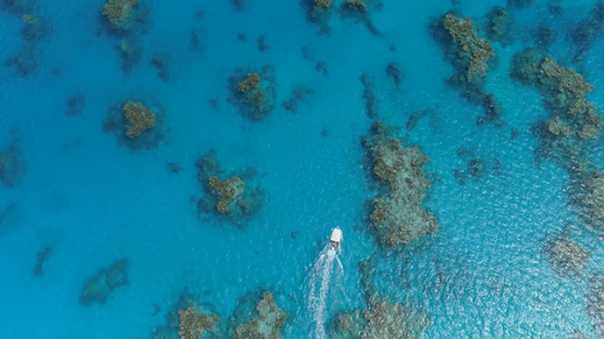 Tubuai, aerial view above a motor boat navigating among the coral reef in the lagoon, 4K UHD