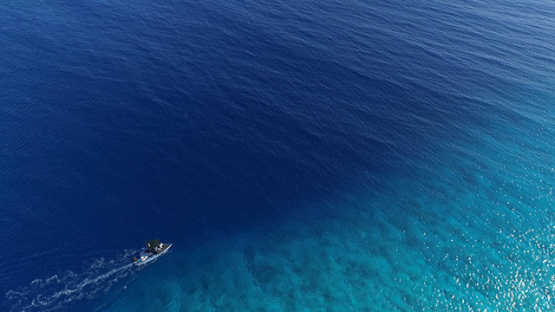Fakarava, aerial view of a motor boat navigating along the coral reef, 4K UHD