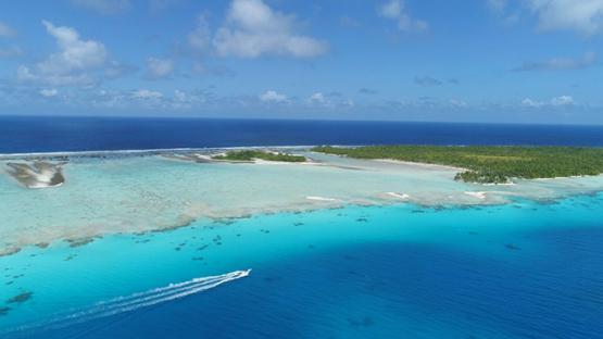 Rangiroa, aerial view of a motor boat navigating in the lagoon along barrier reef and islets, 4K UHD