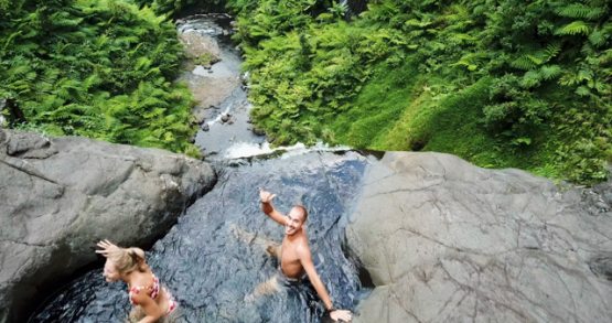 Tahiti 4K drone, aerial diving view of 3 hikers in front of Hitiaa valley waterfall