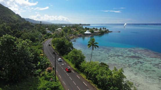 Tahiti, aerial drone view of the coast line and Paea road, following a white bird 