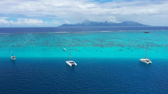 Tahiti Aerial drone view, Sail boat moored in the lagoon, Moorea in the background