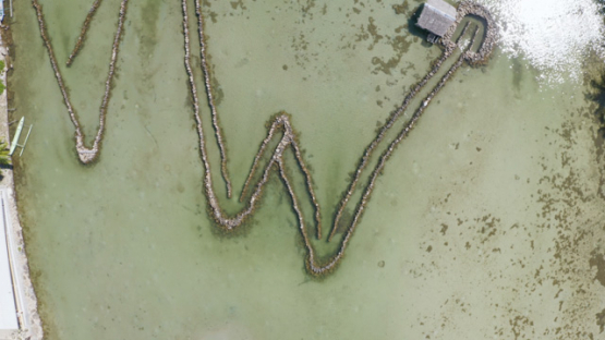 Huahine, aerial view by drone of the traditional stone fish traps of Maeva lake, 4K UHD