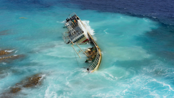 Wreck of a fishing vessel stranded on the reef, battered by the waves, 4K UHD