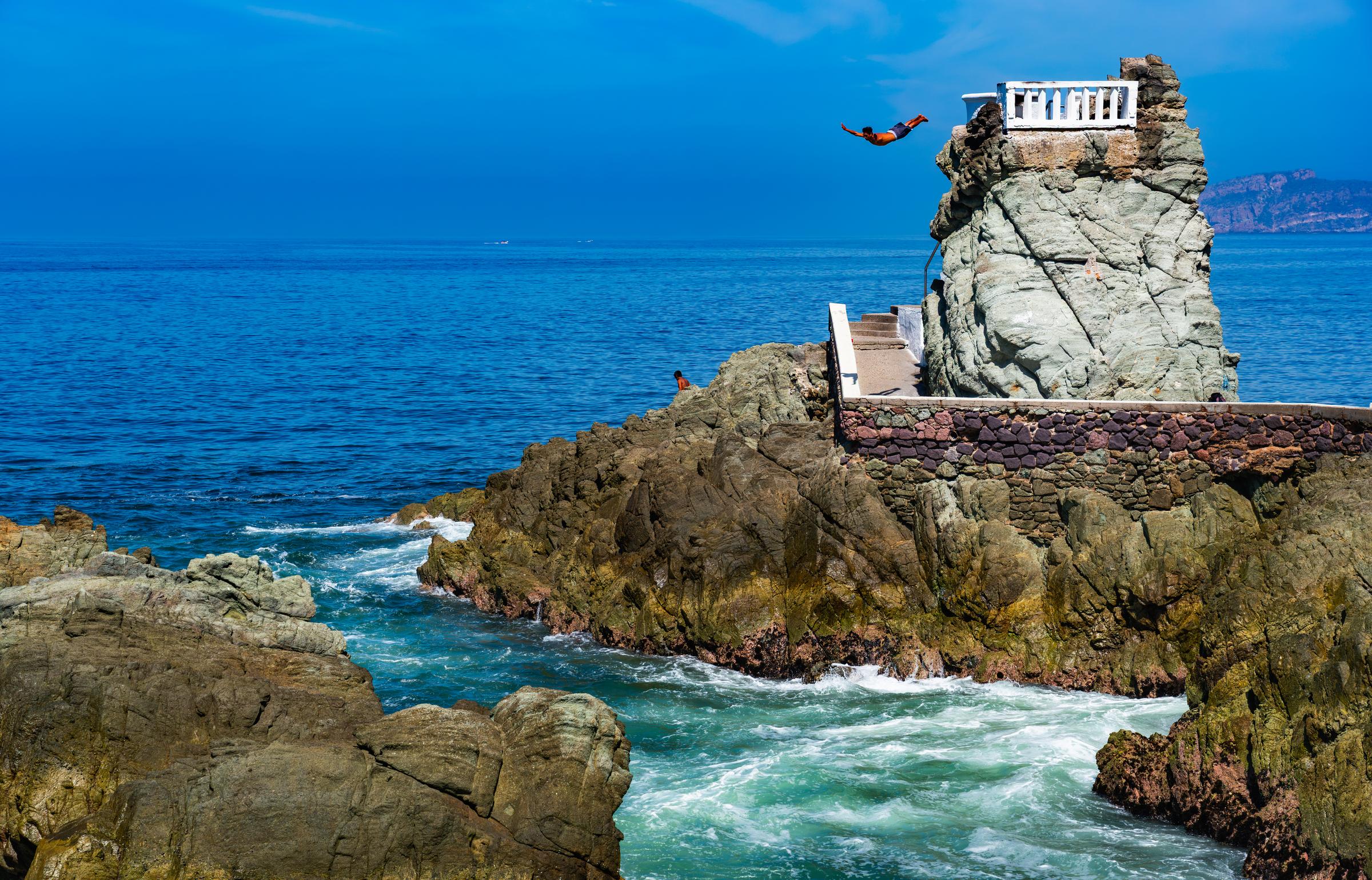 Person diving from rocky cliff into ocean Mazatlan Sinaloa Mexico