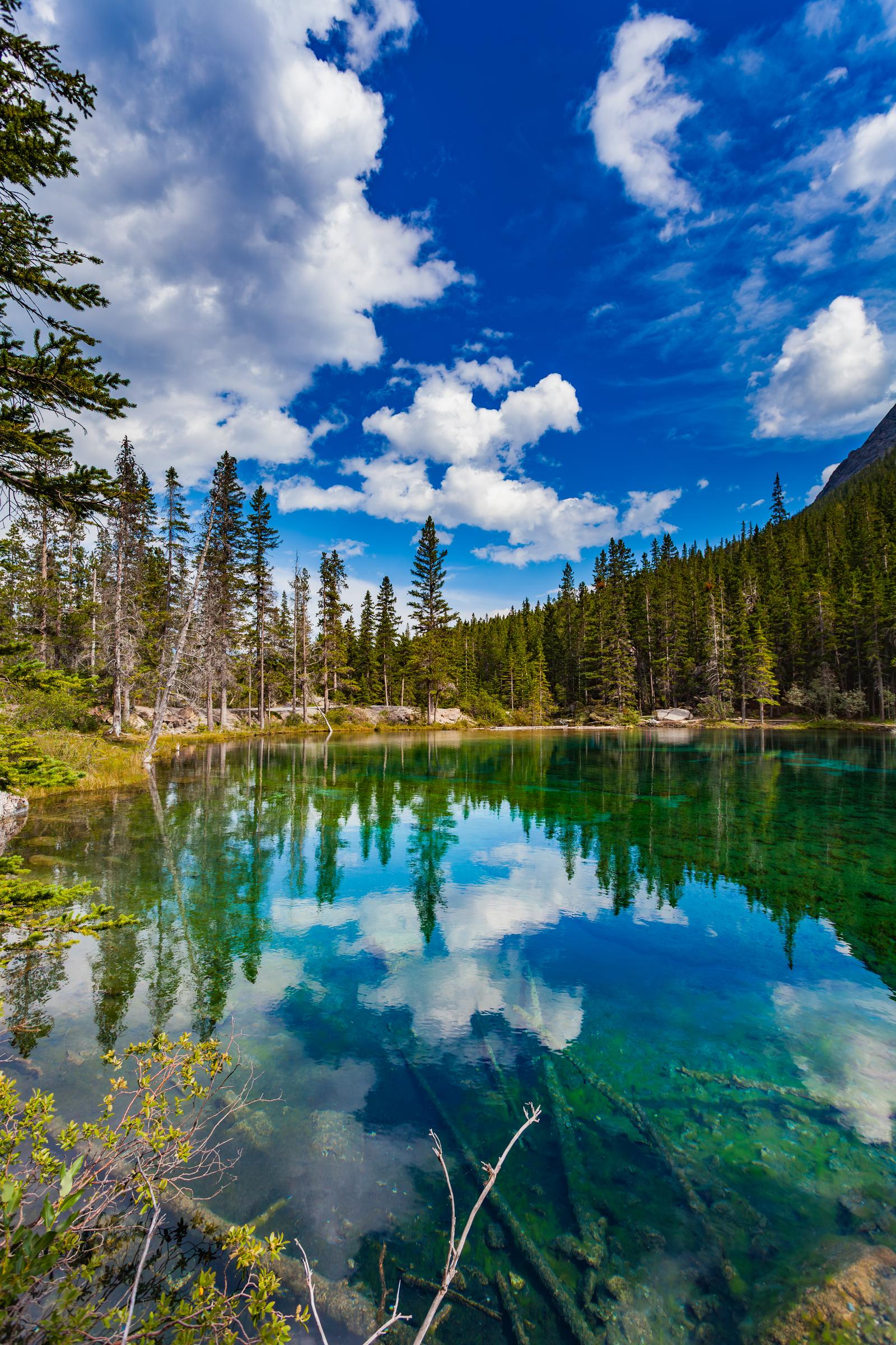Clear lake reflecting sky and trees Grassi Lakes AB Canada